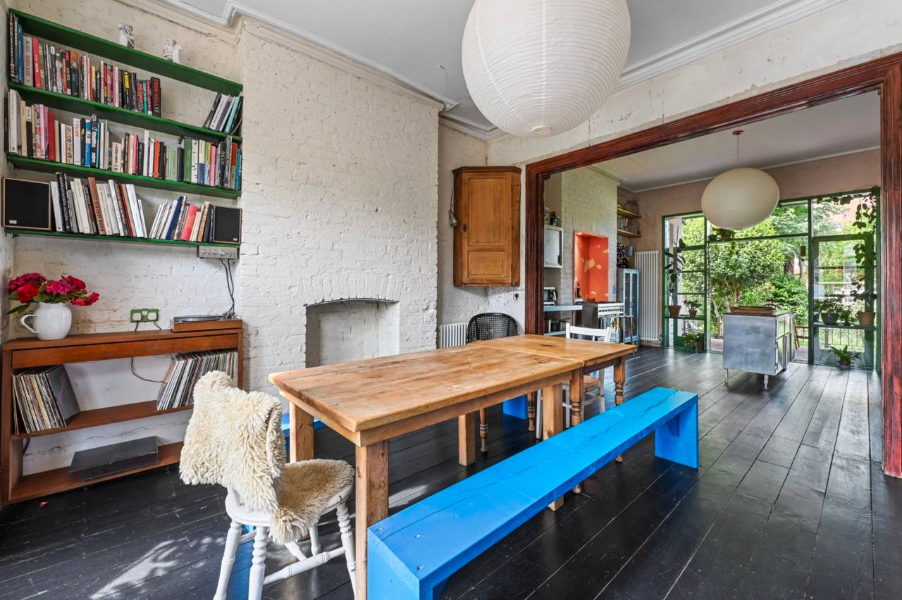 Dining room view looking through to a green framed glass kitchen extension in an East London location house, Love Locations E7.