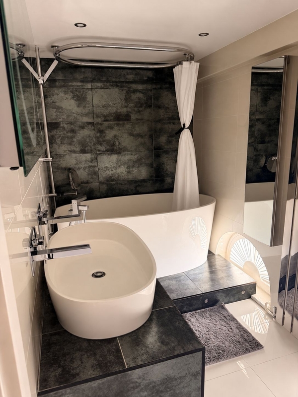 Modern luxury bathroom shoot location in Brixton SW4 from Love Locations, featuring a freestanding oval tub, dark slate-style wall tiles, and white privacy curtains.