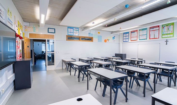 Love Locations contemporary classroom shoot space South East London: Organized secondary school classroom with grey desks, dark blue chairs, and a whiteboard, ideal for educational TV dramas.