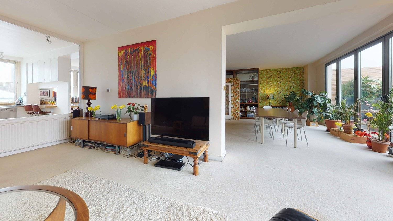 Retro lounge area with dark wood sideboards, tan leather armchairs, and direct access to an open-plan kitchen, Love Locations SW16.