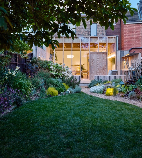 Dusk lighting view of a timber architectural rear extension and lit garden path, Love Locations E17.