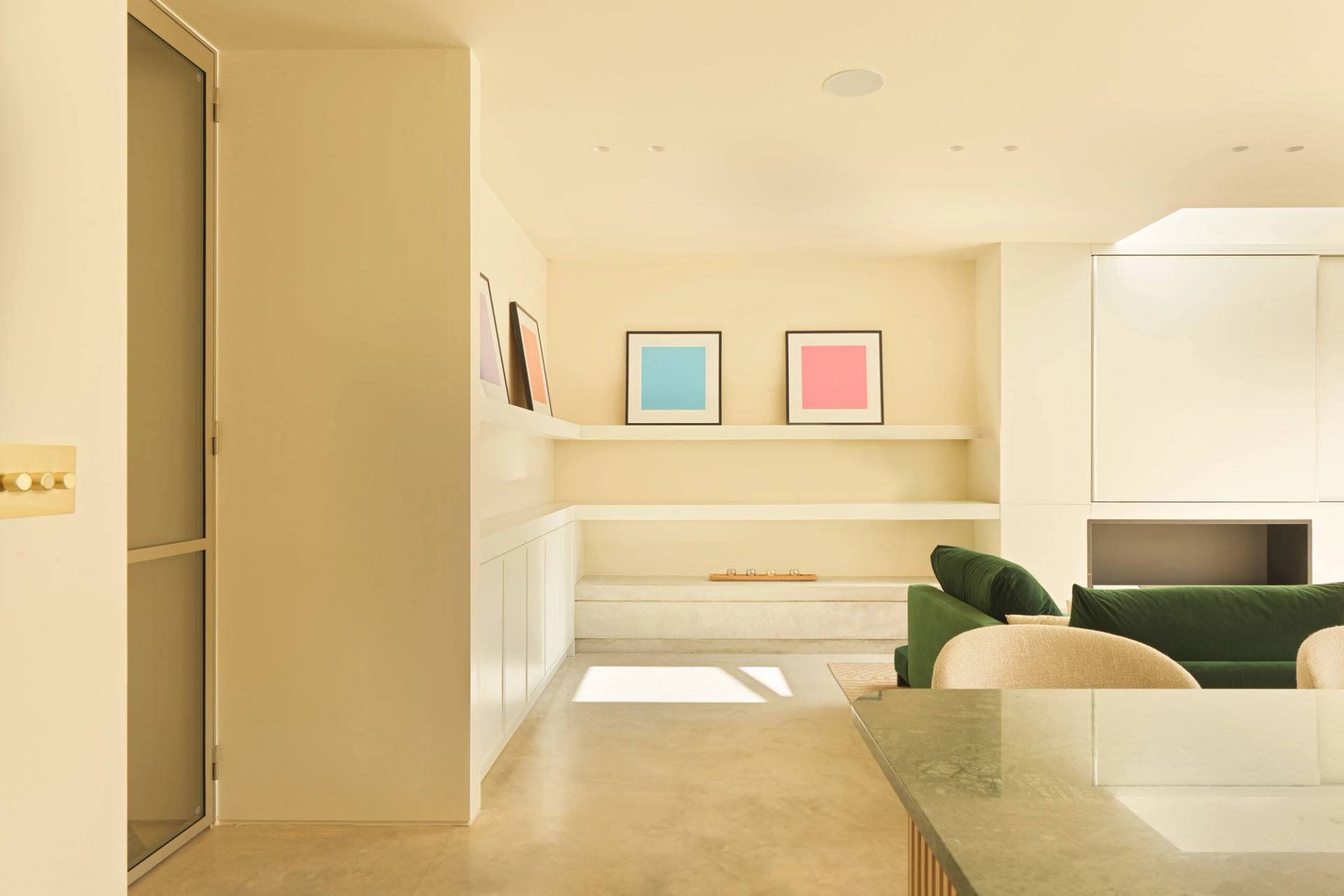 Clean minimalist alcove seating area with neutral plaster finish and recessed wall art display via Love Locations.