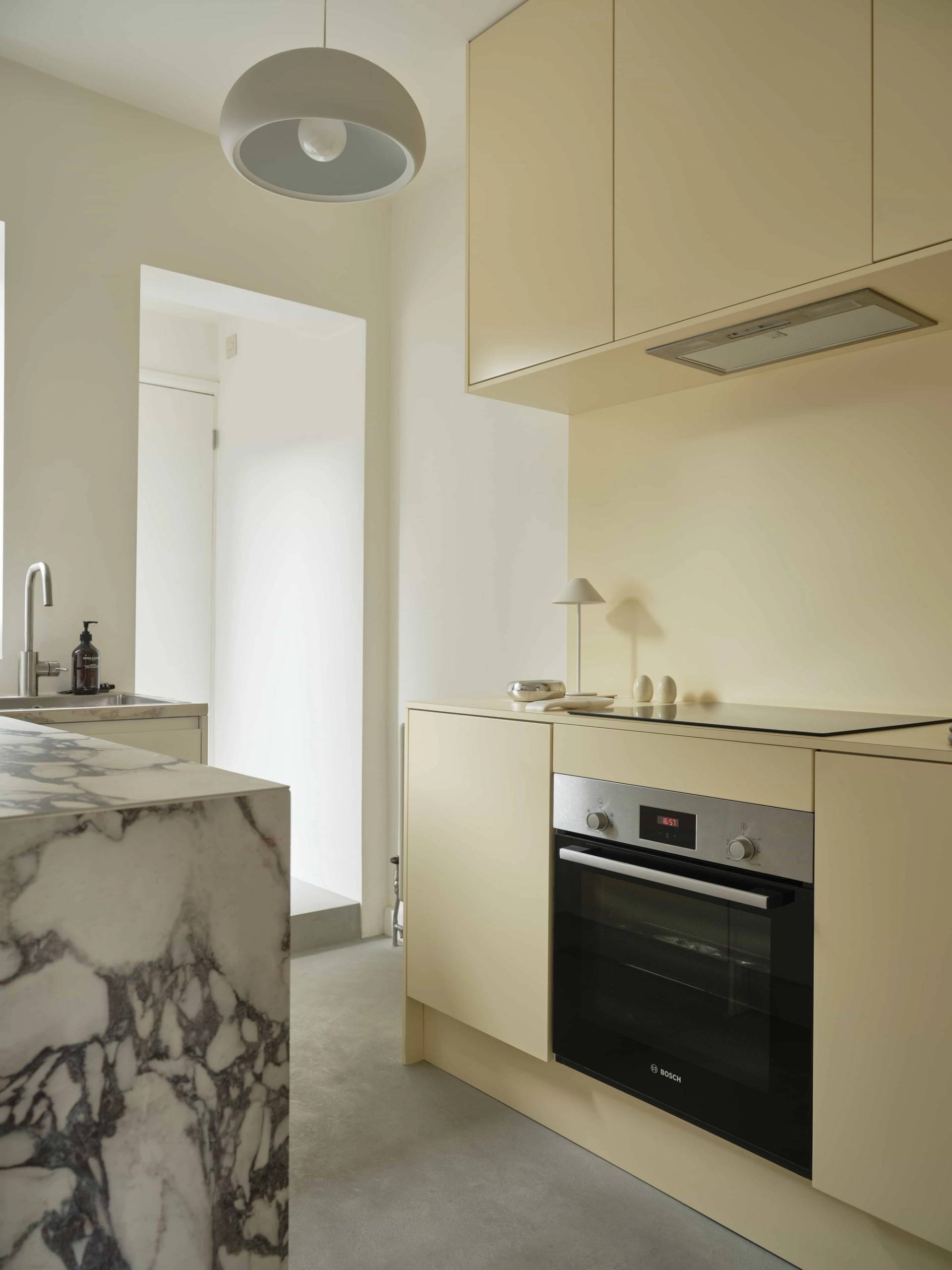 Minimalist kitchen featuring buttercream yellow cabinetry, viola marble counter details, and subtle ambient lighting, Love Locations E4.