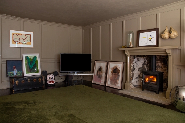 Period sitting room featuring grey panelled walls, open fireplace hearth, TV setup, and green carpet, Love Locations ME13.