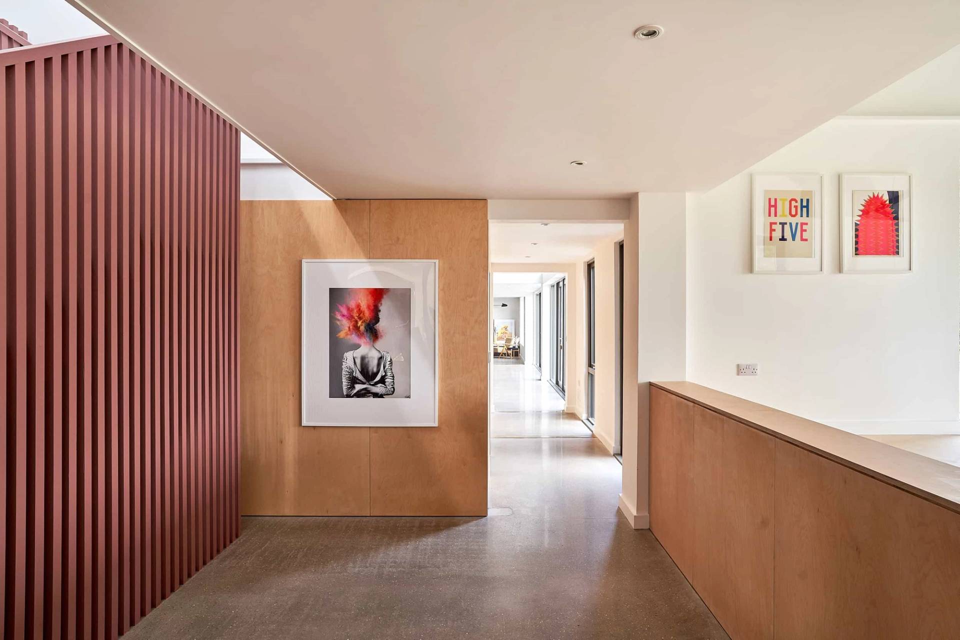 Plywood panelled hallway corridor looking down a bright gallery space toward framed artwork, Love Locations IP30.