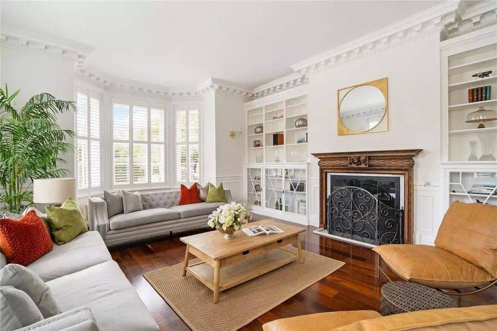 Bright Georgian living room film location in Reading RG10 from Love Locations, featuring bay windows, built-in library bookcases, a wooden coffee table, and open fireplace.