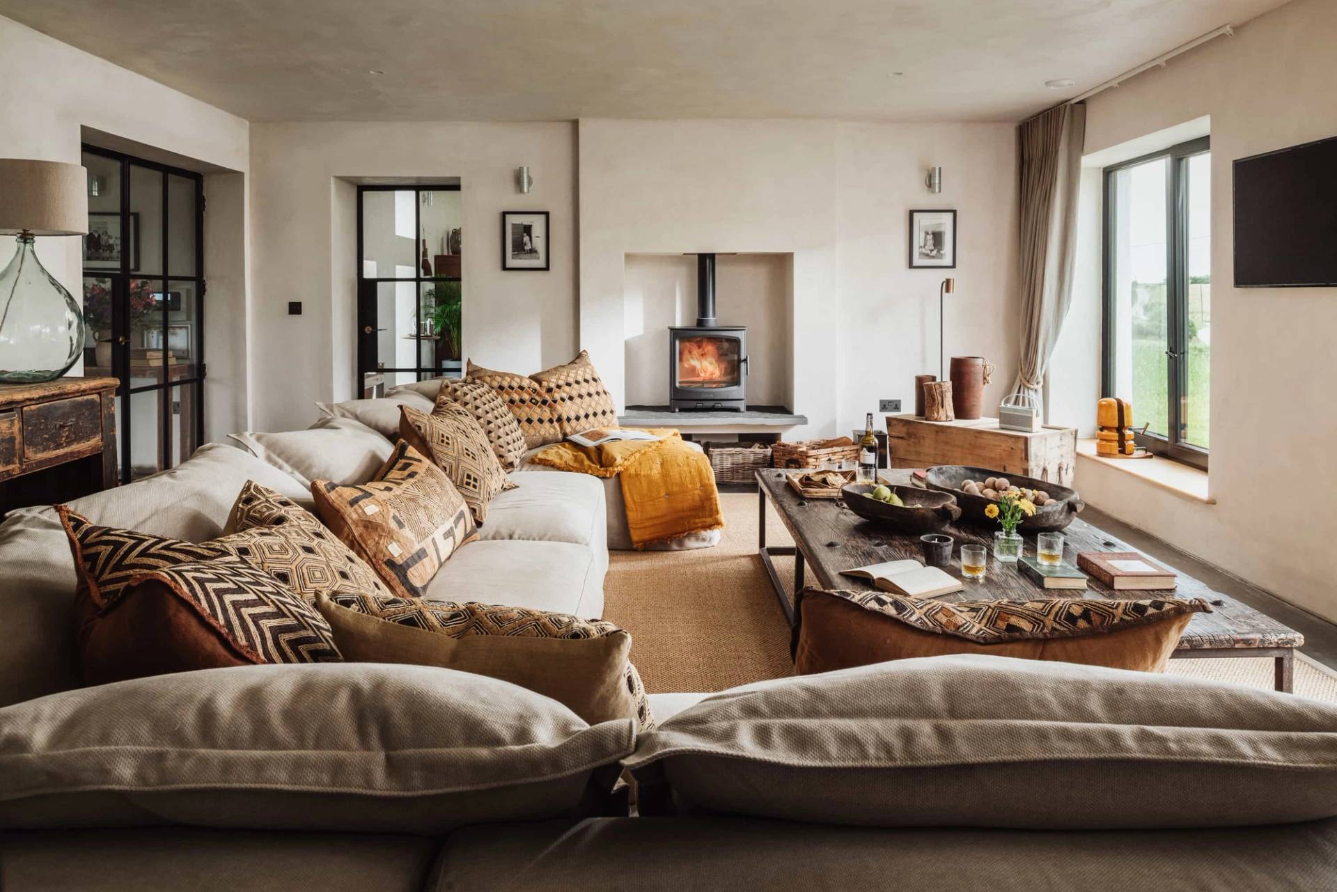 Cozy living room film location in Castleblayney County Monaghan Ireland from Love Locations, featuring neutral sectional seating, patterned cushions, and a double-sided glass fireplace.