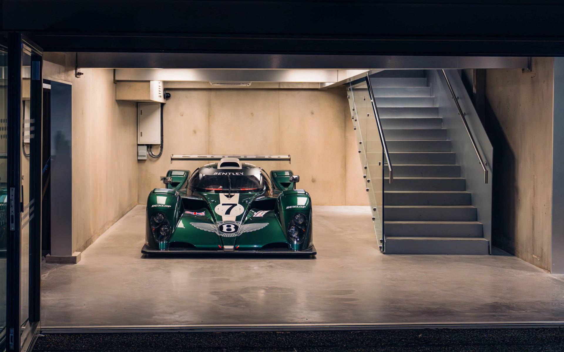 Frontal view of a vintage green race car on polished concrete inside Plonkers Listening Bar through Love Locations.