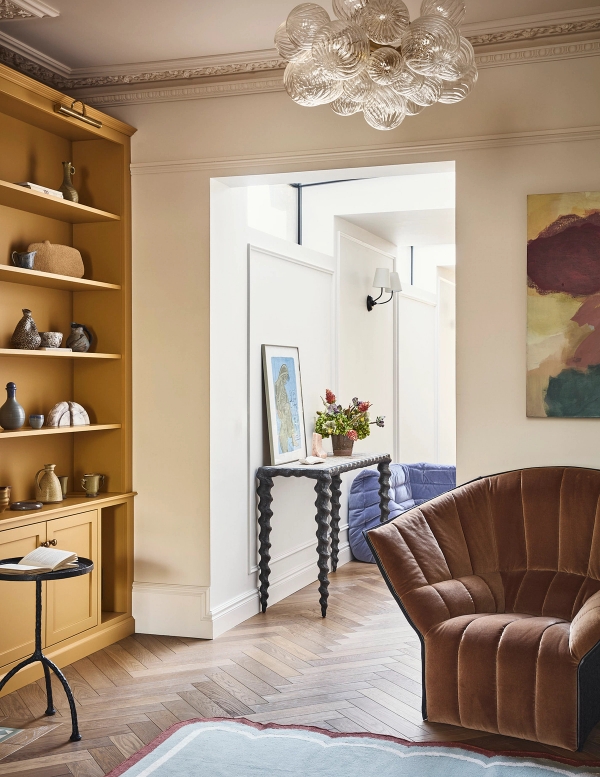 Period living room doorway transition featuring light oak built-in shelves and plush armchair seating, Love Locations SE21.