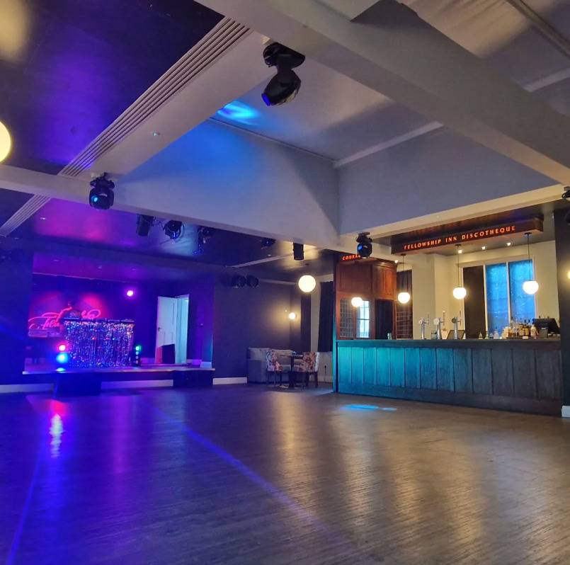 Moodily lit performance hall and music venue location in Lewisham SE6 through Love Locations, featuring blue stage spotlighting and a dark polished bar.