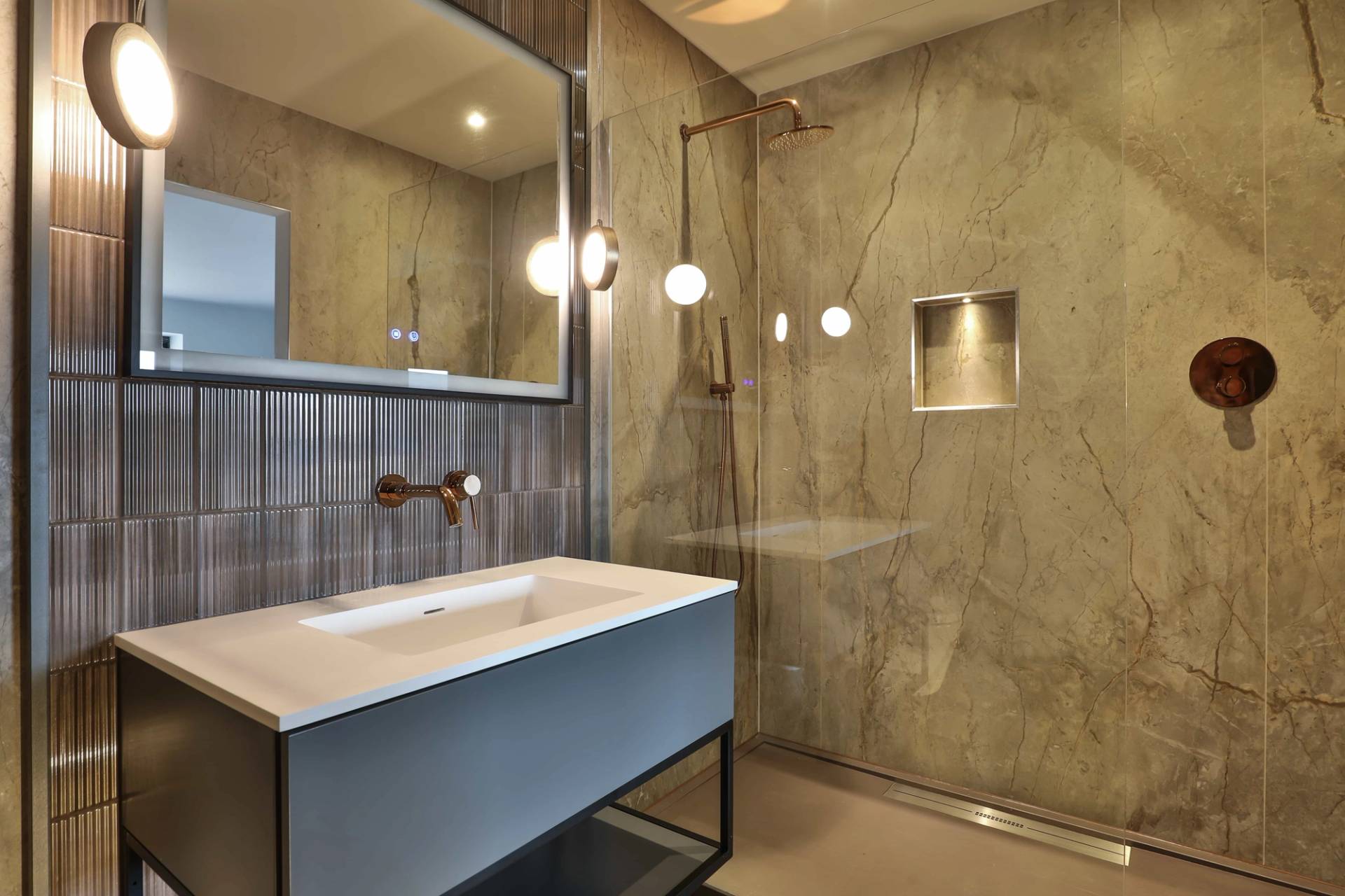 Modern bathroom featuring a blue floating vanity, walk-in glass rain shower, and marble wall tiles, Love Locations CV23.