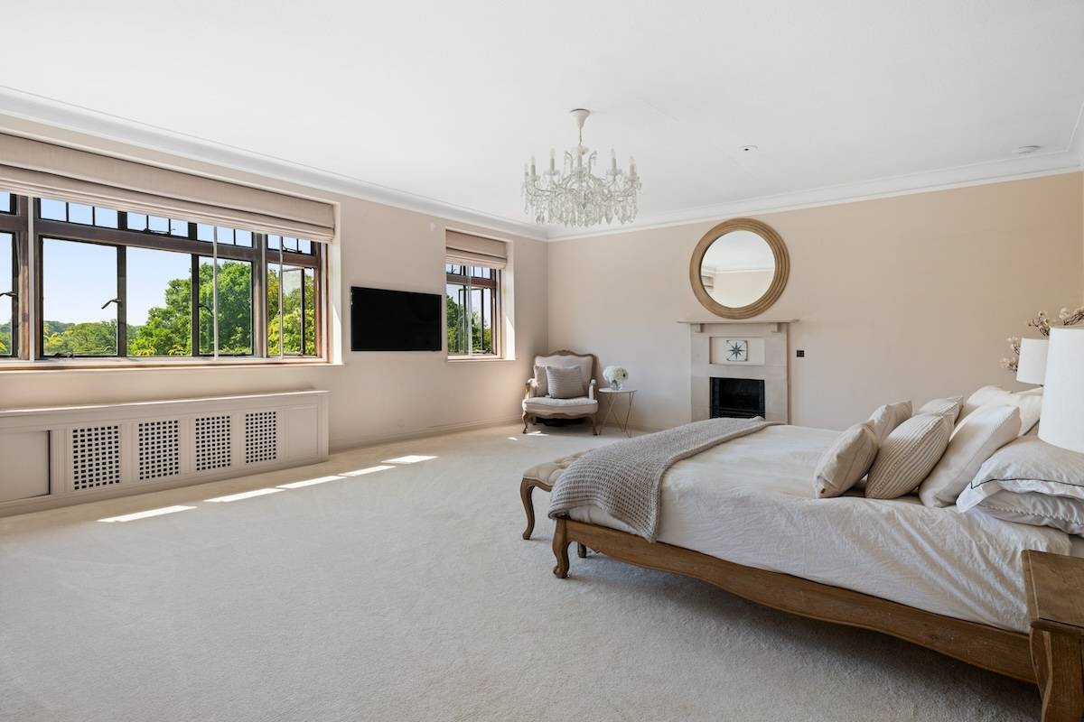 Spacious master bedroom suite featuring a four-poster wooden bed, crystal chandelier, and leaded windows, Love Locations RH13.
