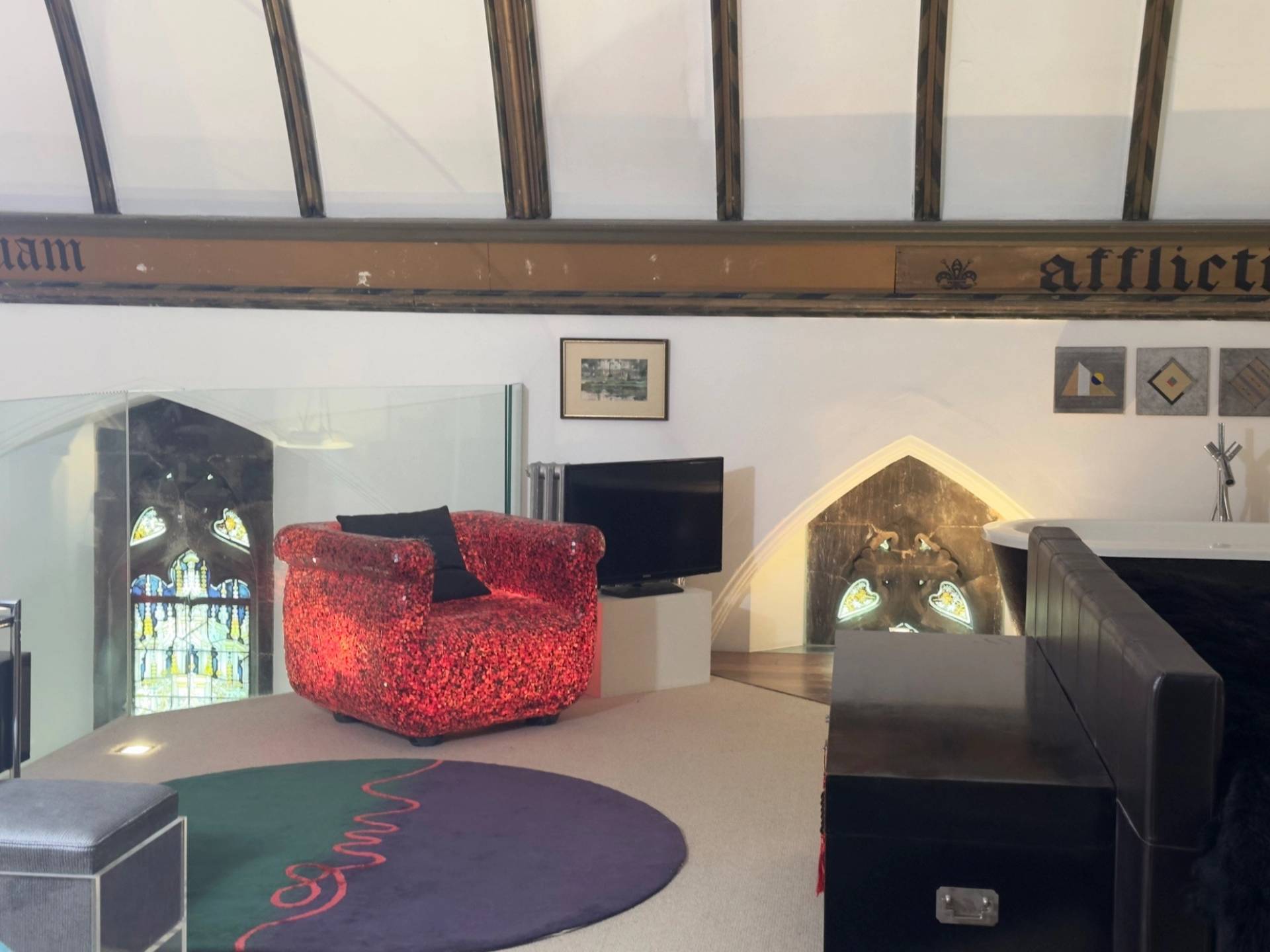 Cozy attic lounge or secondary bedroom space with exposed roof trusses inside a converted chapel in Oval SE5 from Love Locations.