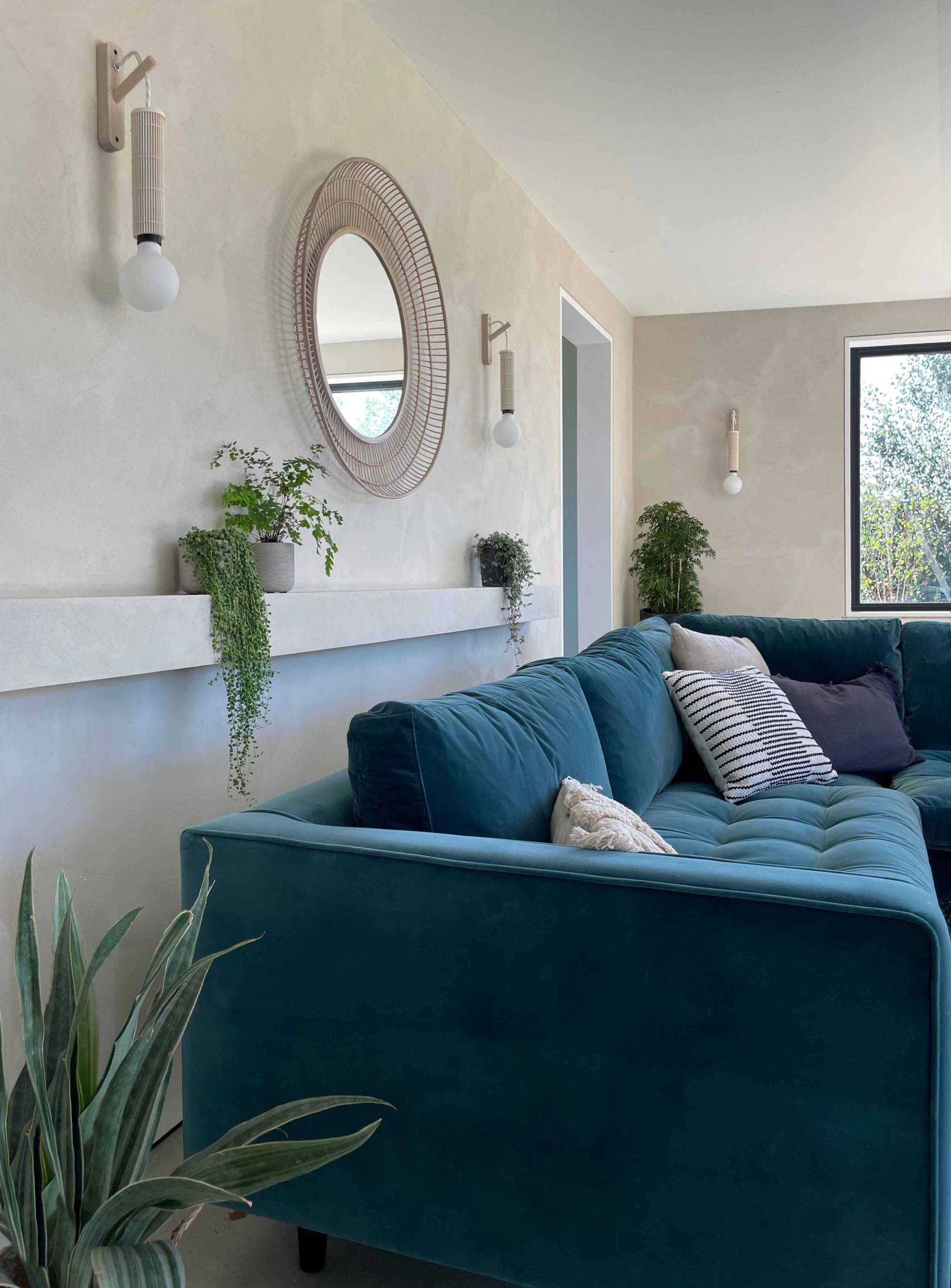 Cozy living room corner featuring a deep teal velvet sofa, oval mirror, and plaster wall finishes, perfect for domestic brand campaigns, Love Locations PO18.