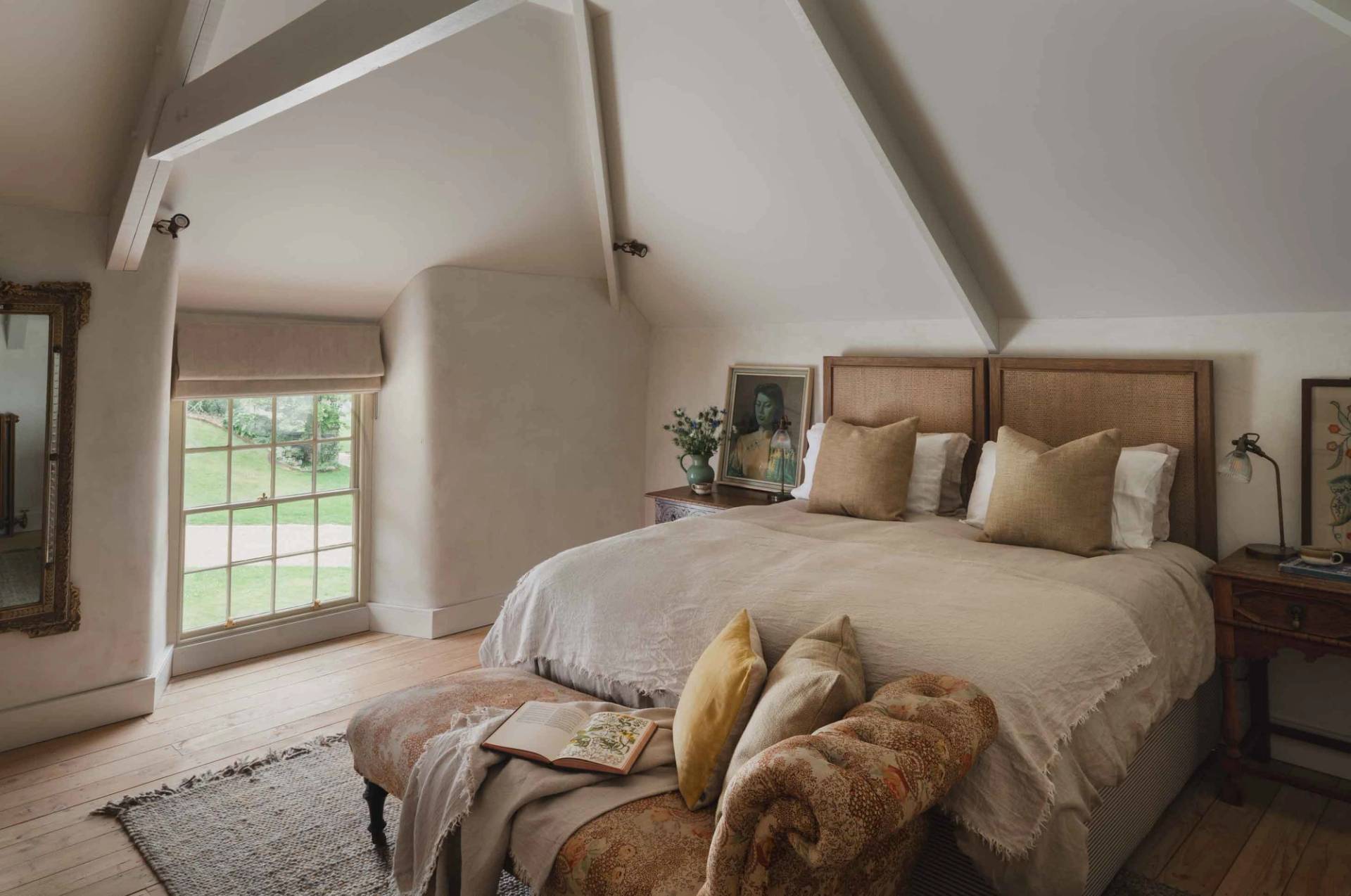 Light-filled master bedroom film location with sloped ceilings and plush neutral bedding in a Newquay manor from Love Locations.