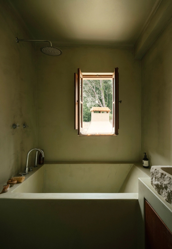 Olive green microcement bathroom with an integrated sunken bathtub and small view window, Love Locations 2705-064.