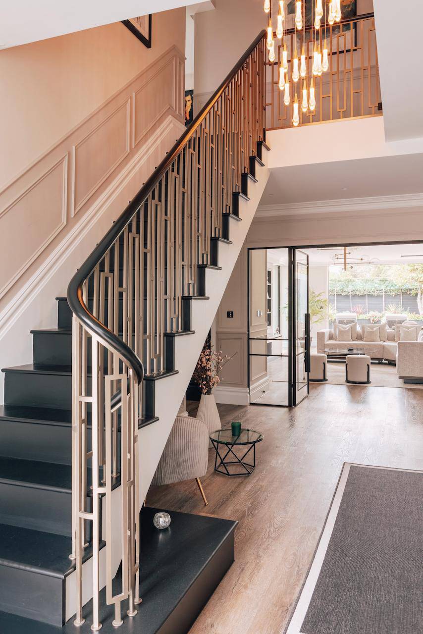 Symmetrical shot of an ornate grand staircase with black handrails and crittall door entryways, Love Locations.