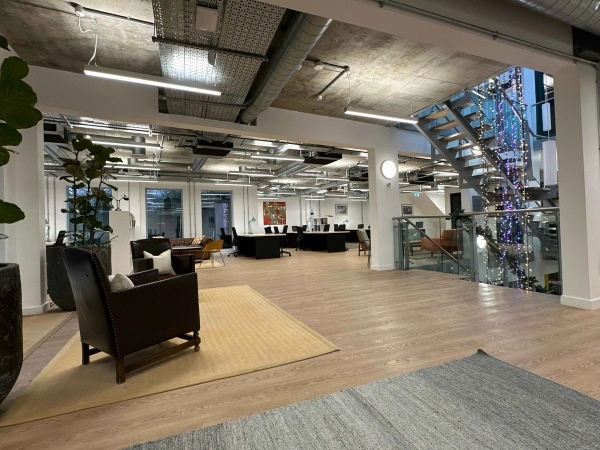 Bright open office space with industrial-style exposed ceiling and metal staircase.