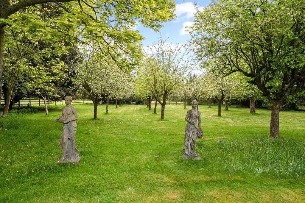 Classical stone garden statues positioned beneath mature orchard trees in private country estate grounds through Love Locations.