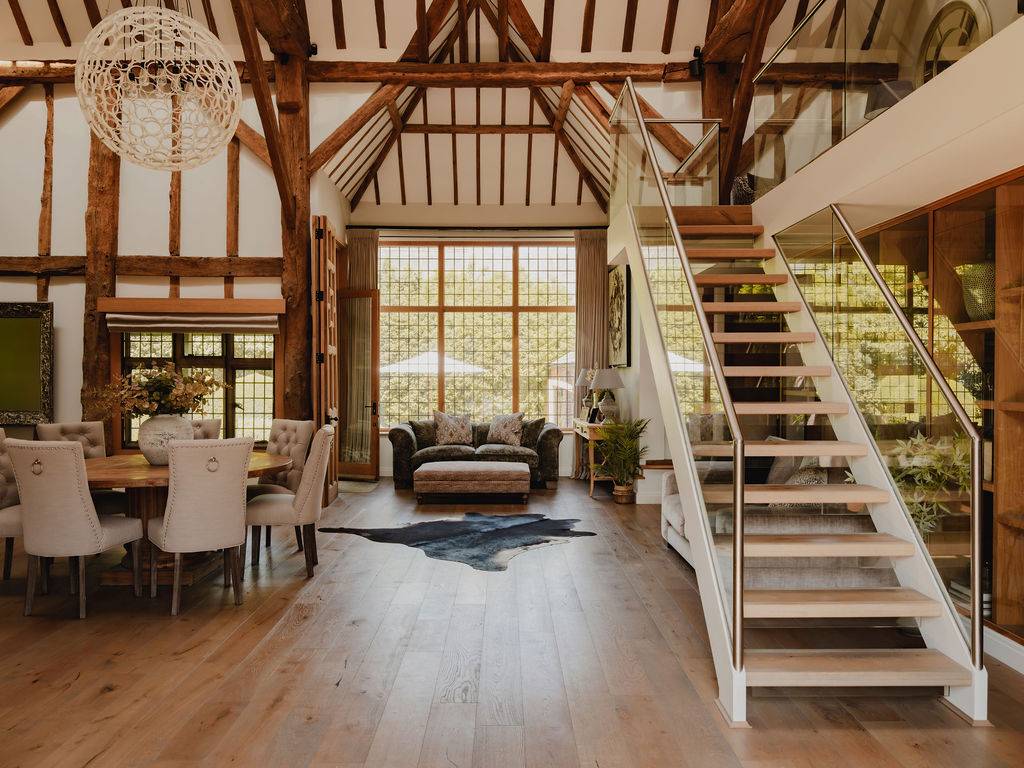 Expansive barn interior looking towards towering multi-pane glass doors and a floating wooden staircase, Love Locations.