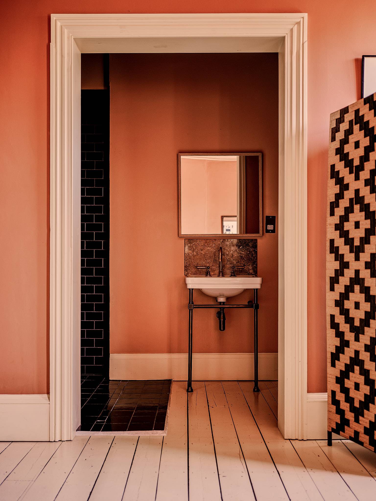 Ensuite bathroom doorway view showing a metal washstand sink and terracotta walls, Love Locations.