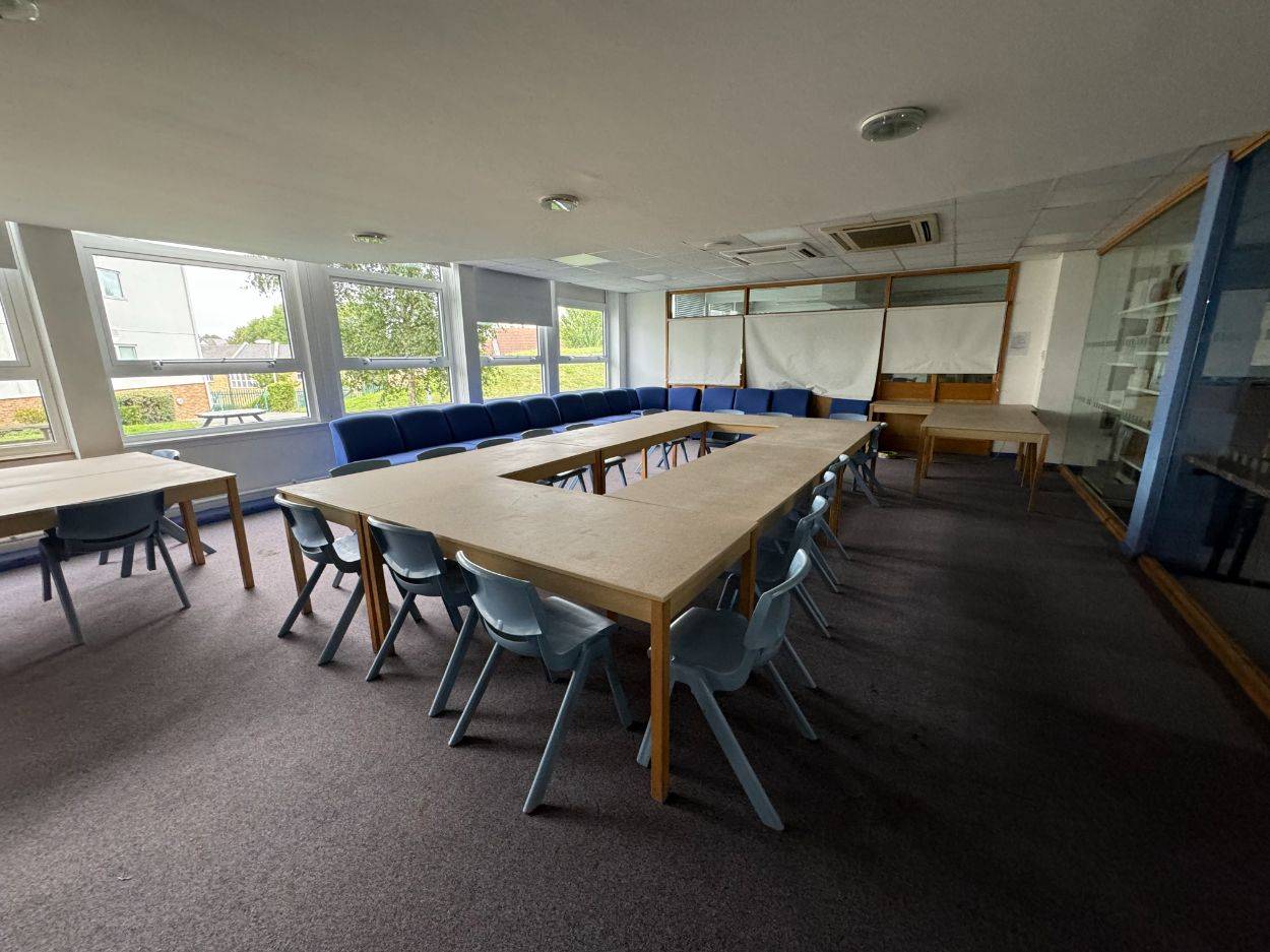 Spacious conference room or school seminar room filming space featuring a rectangular table layout and blue chairs through Love Locations.