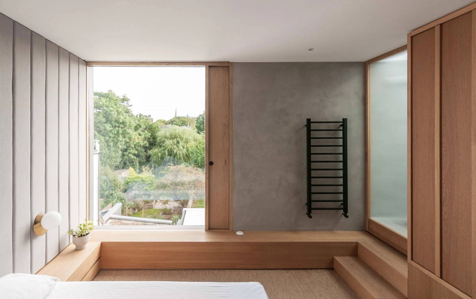 Modern bedroom lounge area in Hackney London N16 through Love Locations, featuring built-in low seating steps and large garden windows.