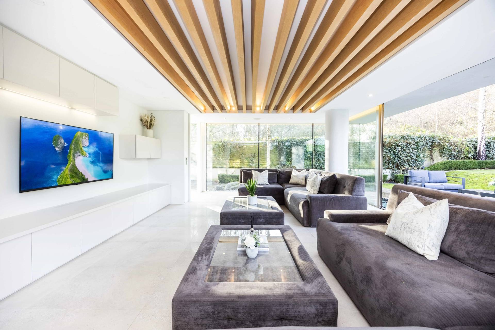 Low-angle perspective of a grey velvet sofa set against a slatted timber ceiling feature wall, Love Locations WD7.