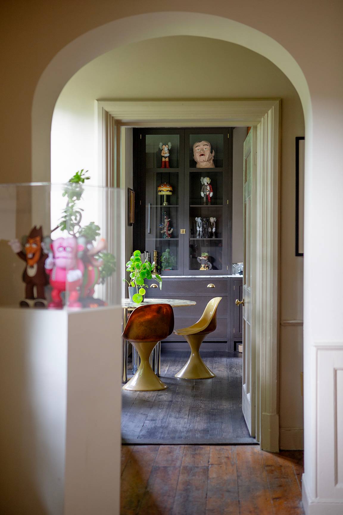 Doorway view looking into a cozy dining nook with dark wood display cabinets and yellow chairs, Love Locations ME13.