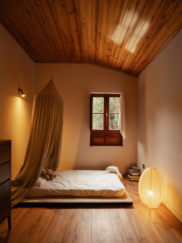 Minimalist low-platform bed with delicate bed canopy netting and warm globe floor lamp, Love Locations 2705-064.