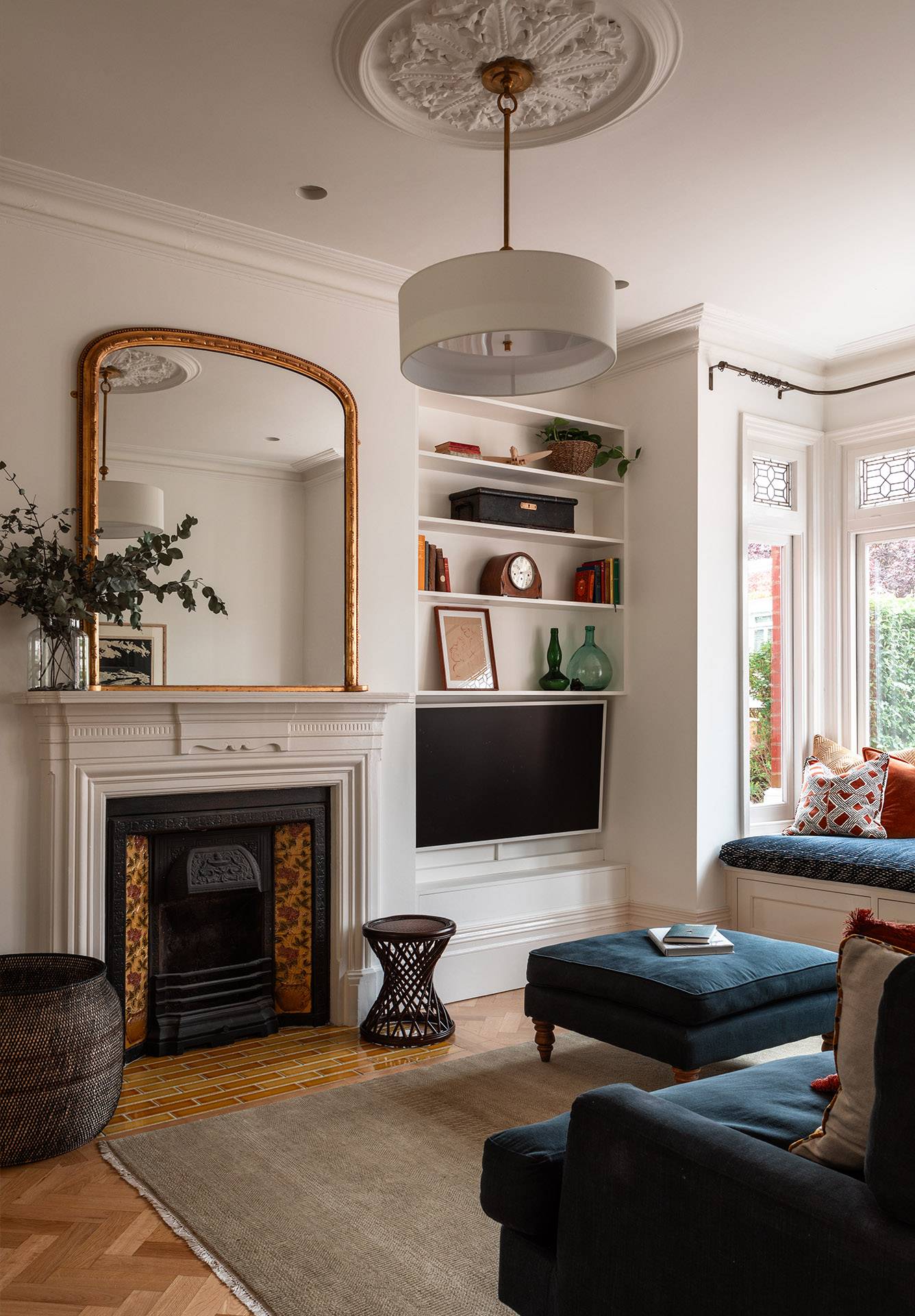 Cozy snug room corner with a traditional cast iron fireplace, gold arched mirror, and built-in window seating, ideal for intimate film scenes, Love Locations TW1.