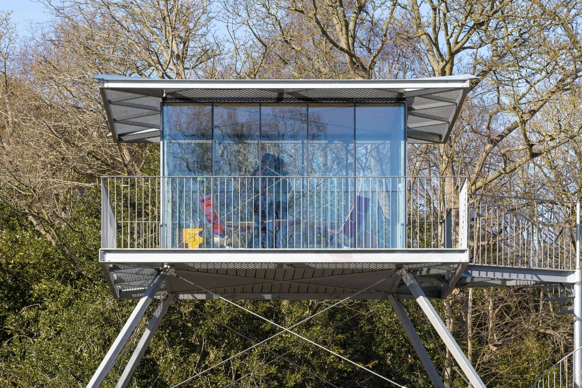Elevated glass lookout studio box supported by steel stilts over a dark timber ground floor, Love Locations IP17.