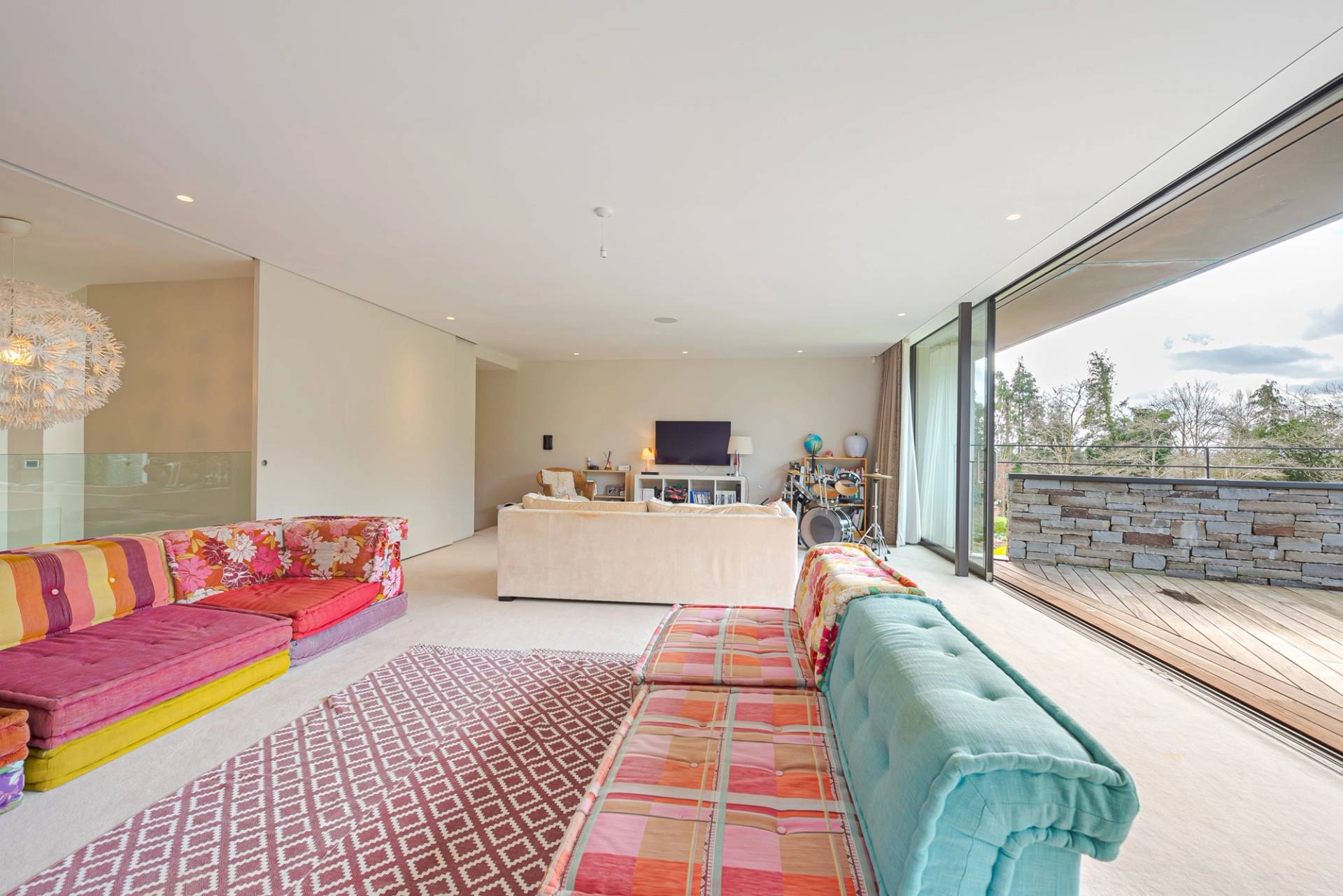 Family sitting room featuring colorful velvet sofas, pink pattern rug, and garden views, Love Locations KT2.