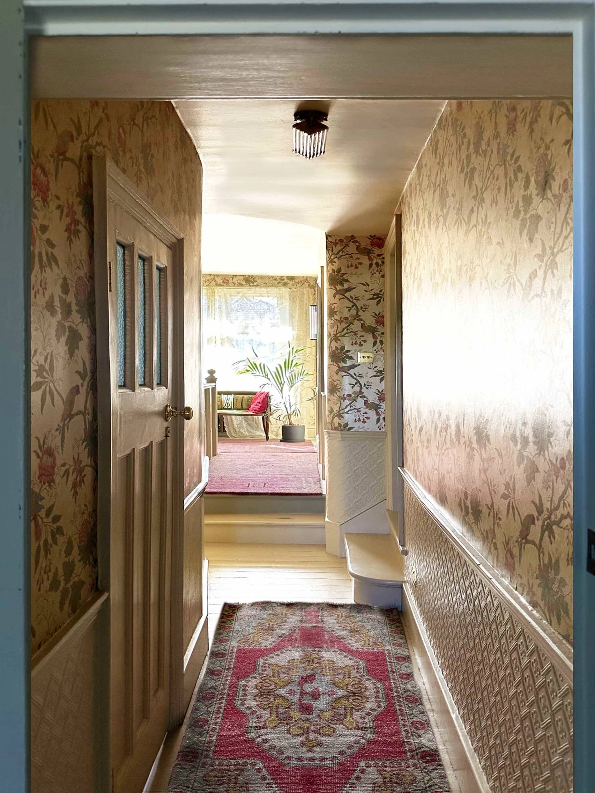 Wallpapered hallway corridor leading into a bright bedroom with red patterned runner rug, Love Locations N13.