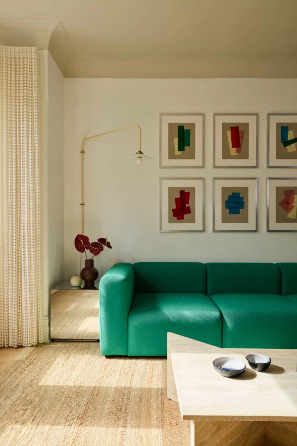 Love Locations vibrant sitting room location Lewisham: Mid-century style lounge featuring a plush emerald green velvet couch and a grid gallery wall, perfect for fashion portraiture.