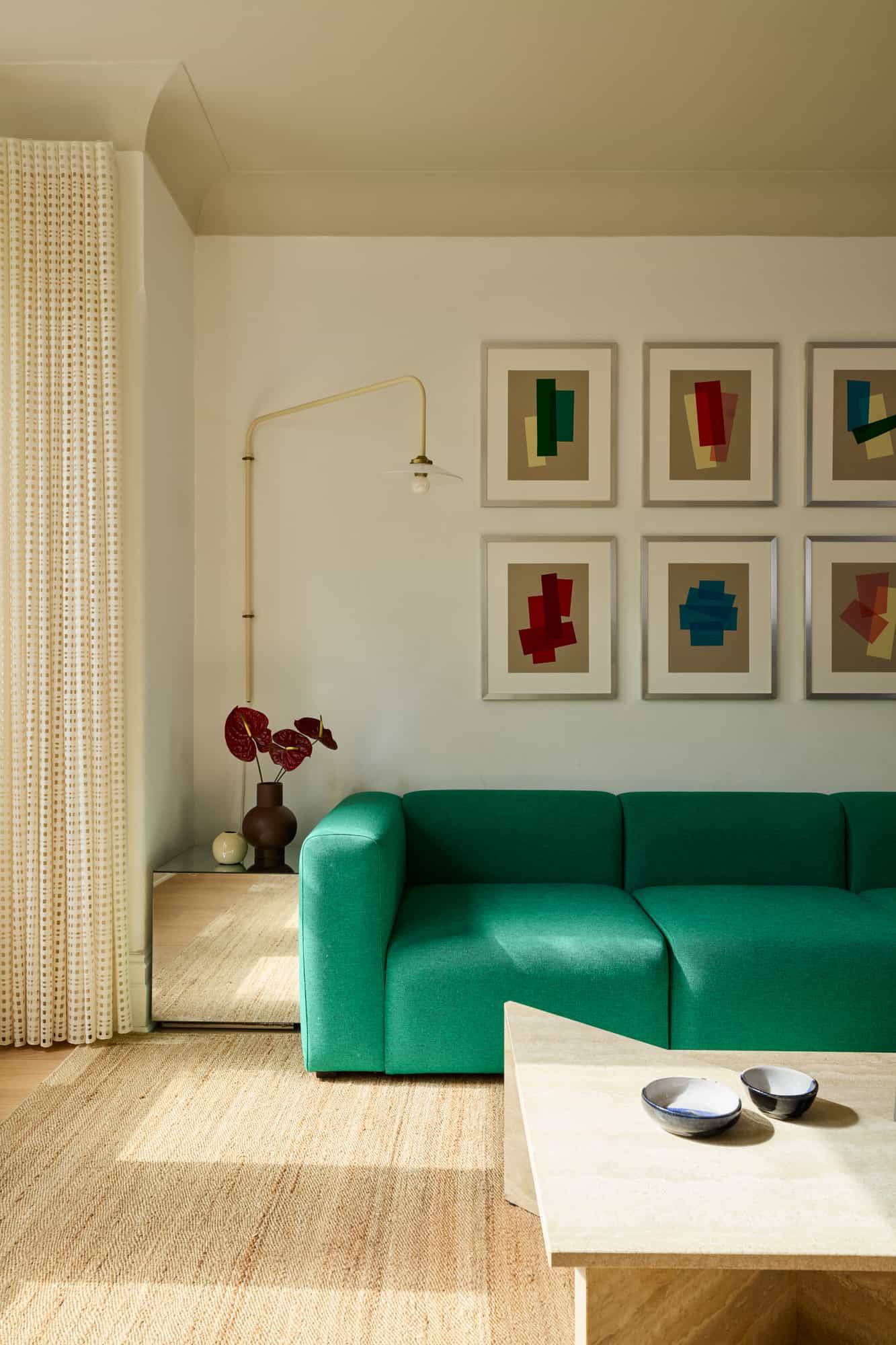 Love Locations vibrant sitting room location Lewisham: Mid-century style lounge featuring a plush emerald green velvet couch and a grid gallery wall, perfect for fashion portraiture.