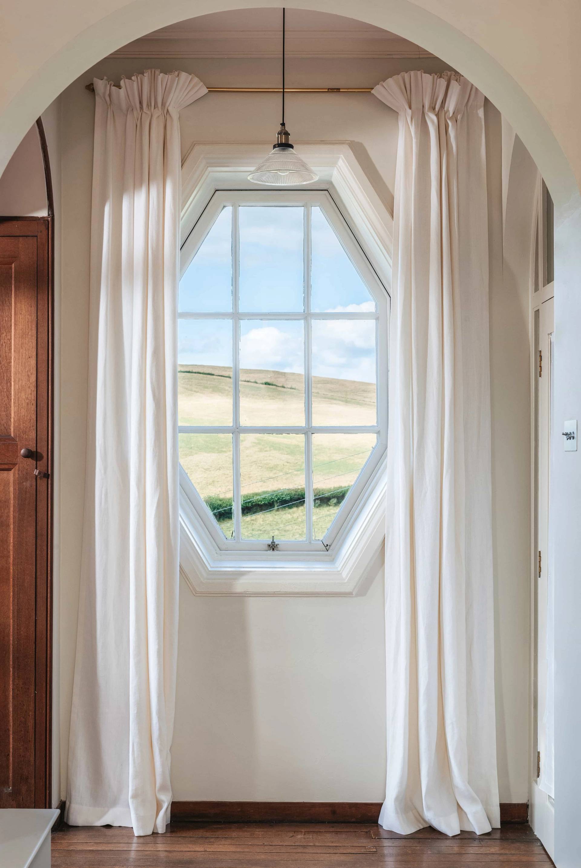 Unique octagonal window frame casting natural light into a country estate interior via Love Locations.