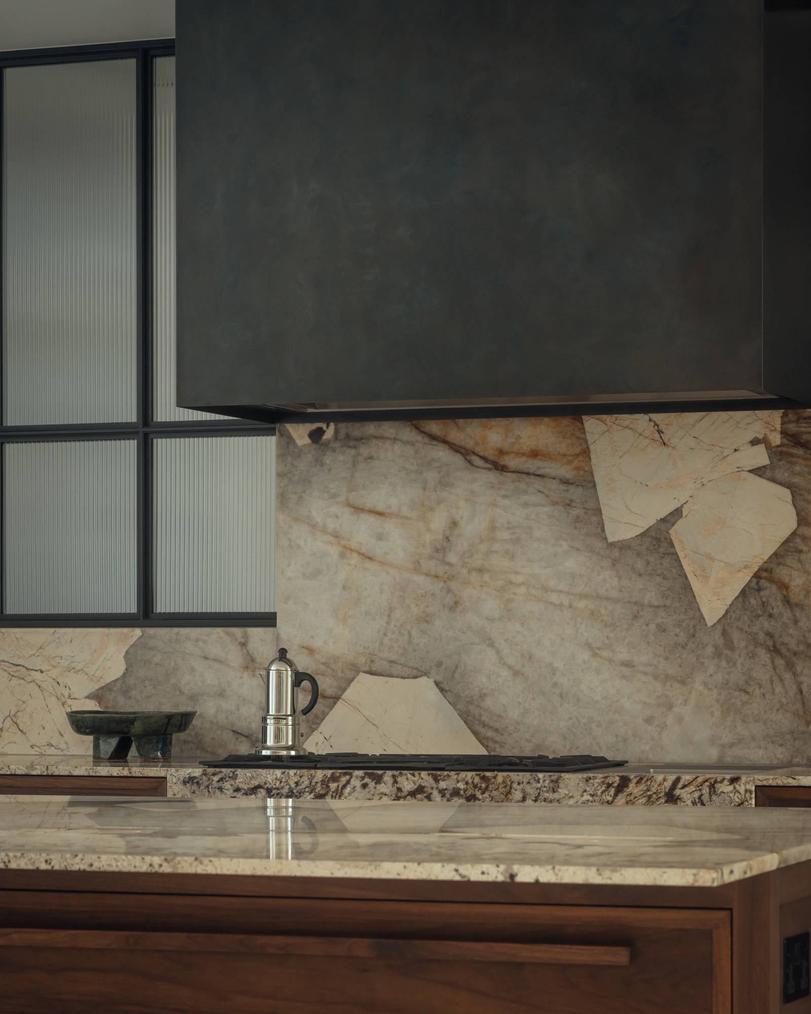 Detailed close-up of a dramatic raw marble slab splashback and black kitchen extractor hood in an architectural home, ideal for kitchenware product marketing, Love Locations SO20.