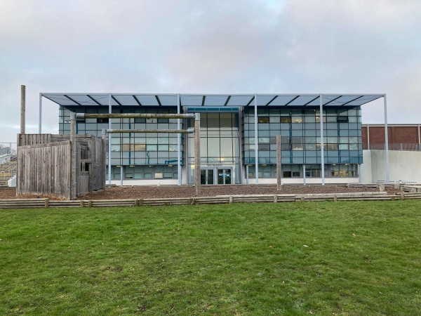 Love Locations architectural school campus location Chelmsford: Front view of a sleek, symmetrical educational facility with extensive structural glass panels, perfect for television dramas and commercial backgrounds.