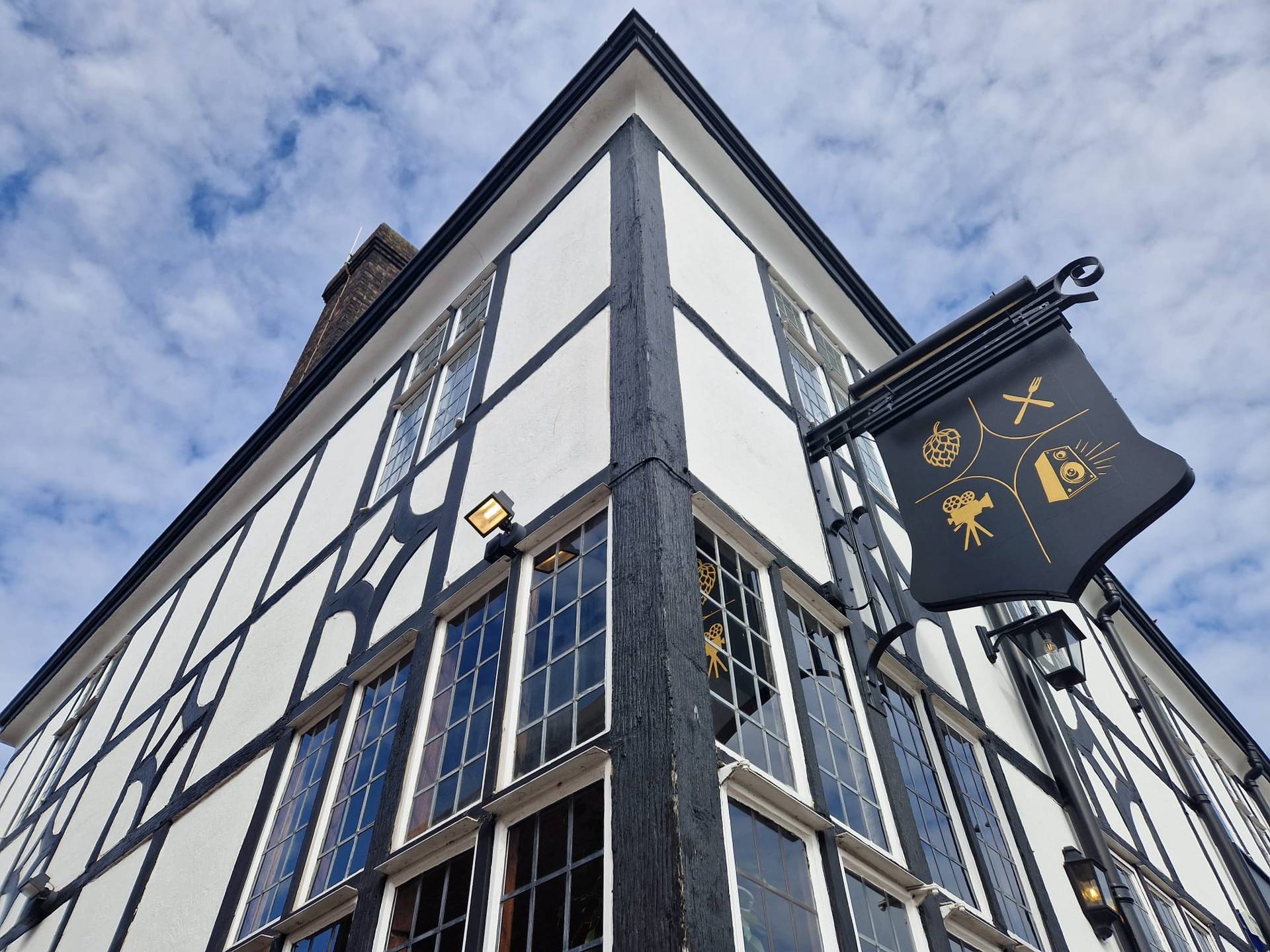 Architectural exterior detail of a historic Mock-Tudor pub building and hanging pub sign in Lewisham SE6 from Love Locations.