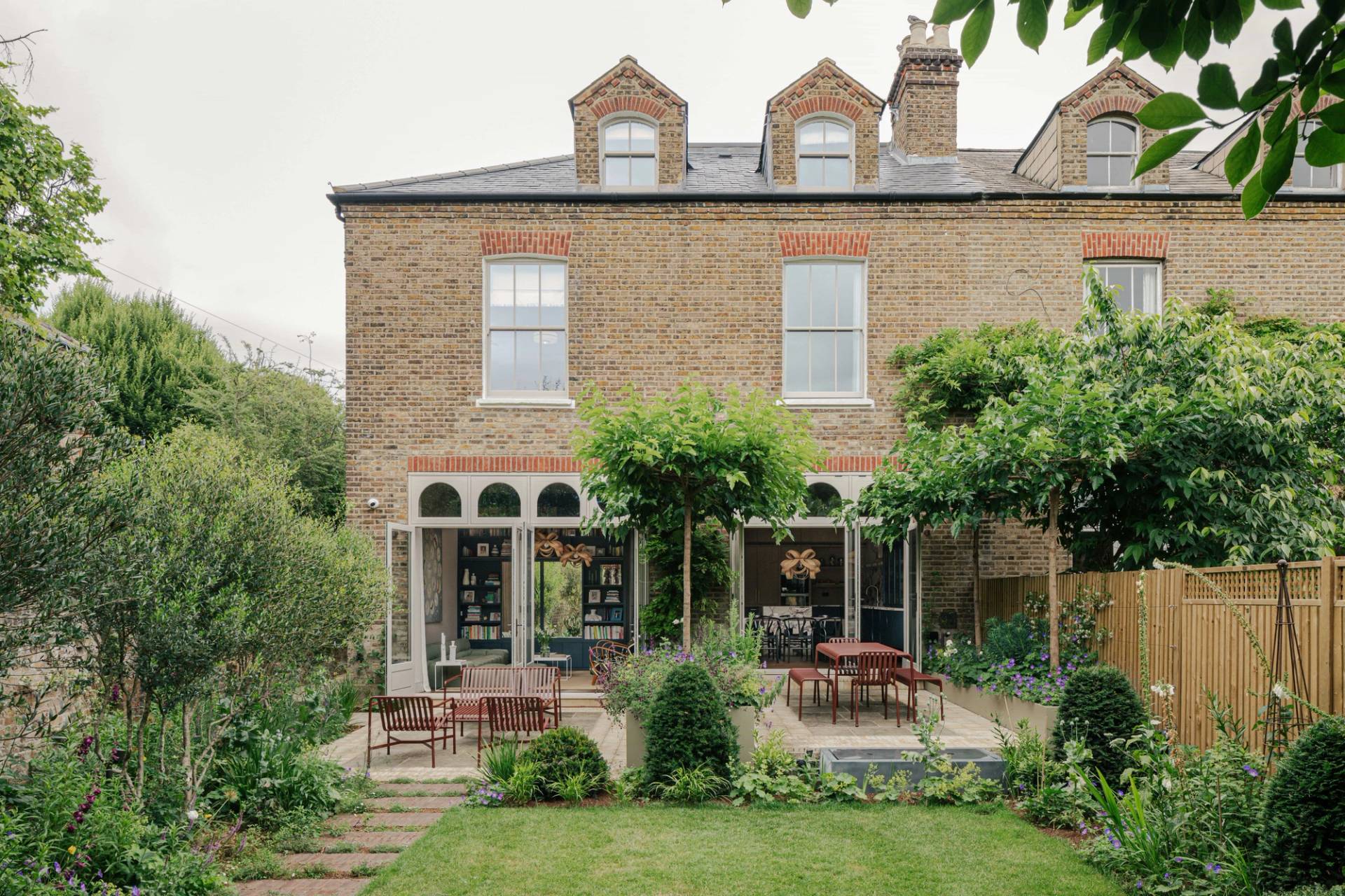 Rear facade shot of a stately period home in Barnes, SW13 with arched glass windows and pleached trees, Love Locations.