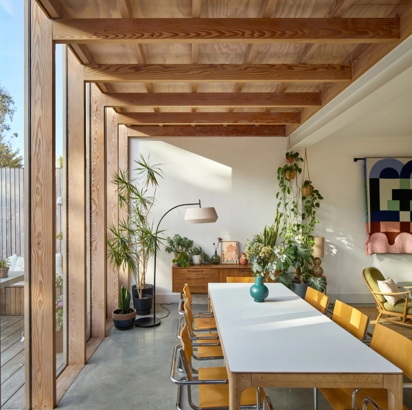 Modern open-plan living and dining area with long white dining table, timber framing, and skylight windows, Love Locations E17.