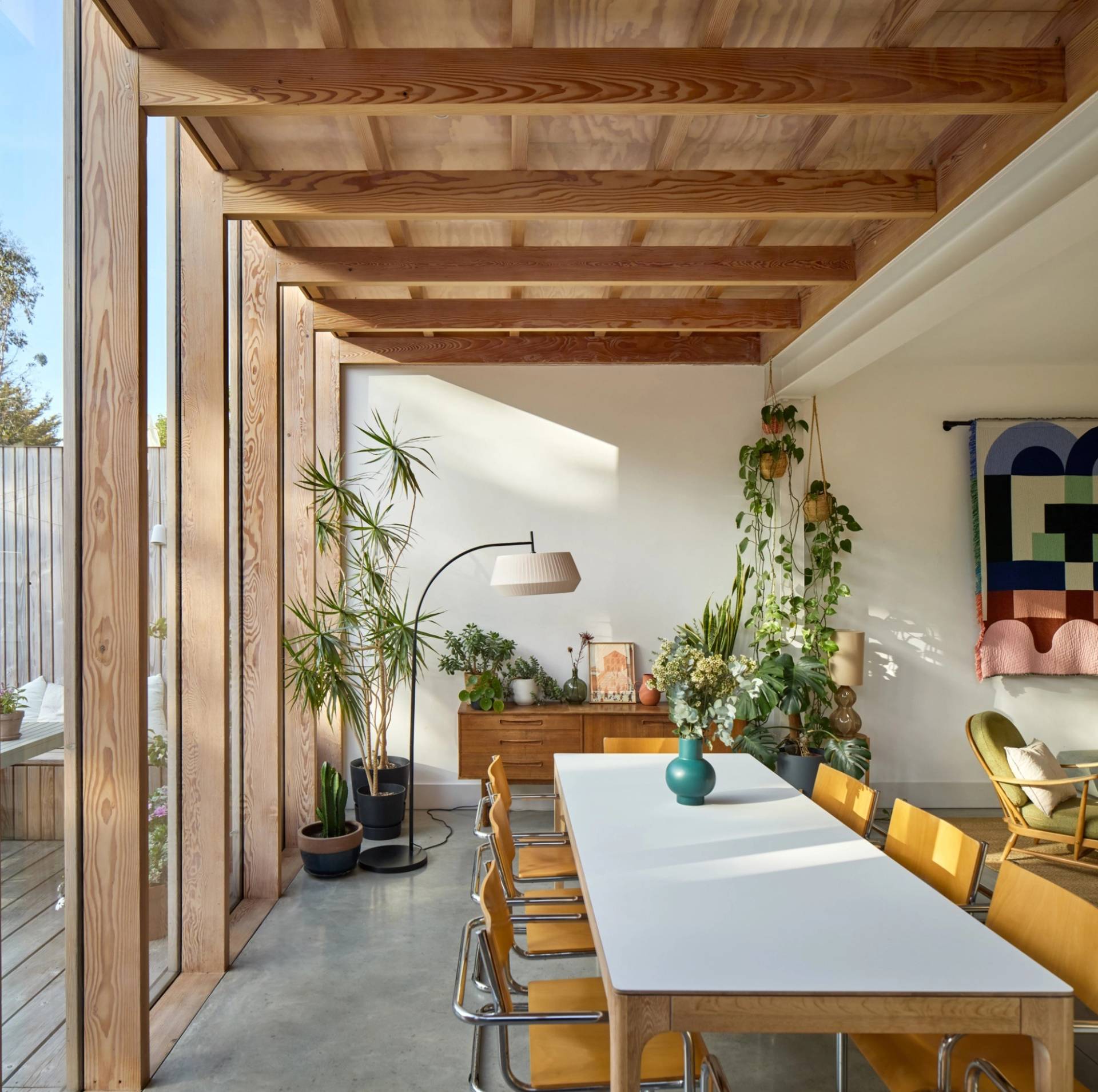 Modern open-plan living and dining area with long white dining table, timber framing, and skylight windows, Love Locations E17.