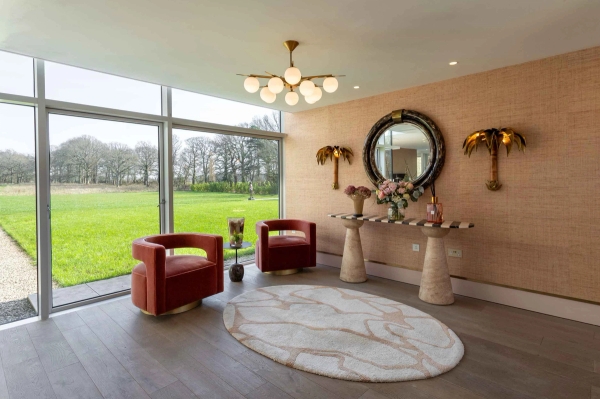 Love Locations designer residential space Godalming: Elegant dressing or seating nook with rich terracotta tones, a pedestal console table, and a large round mirror, optimized for fashion portraiture.