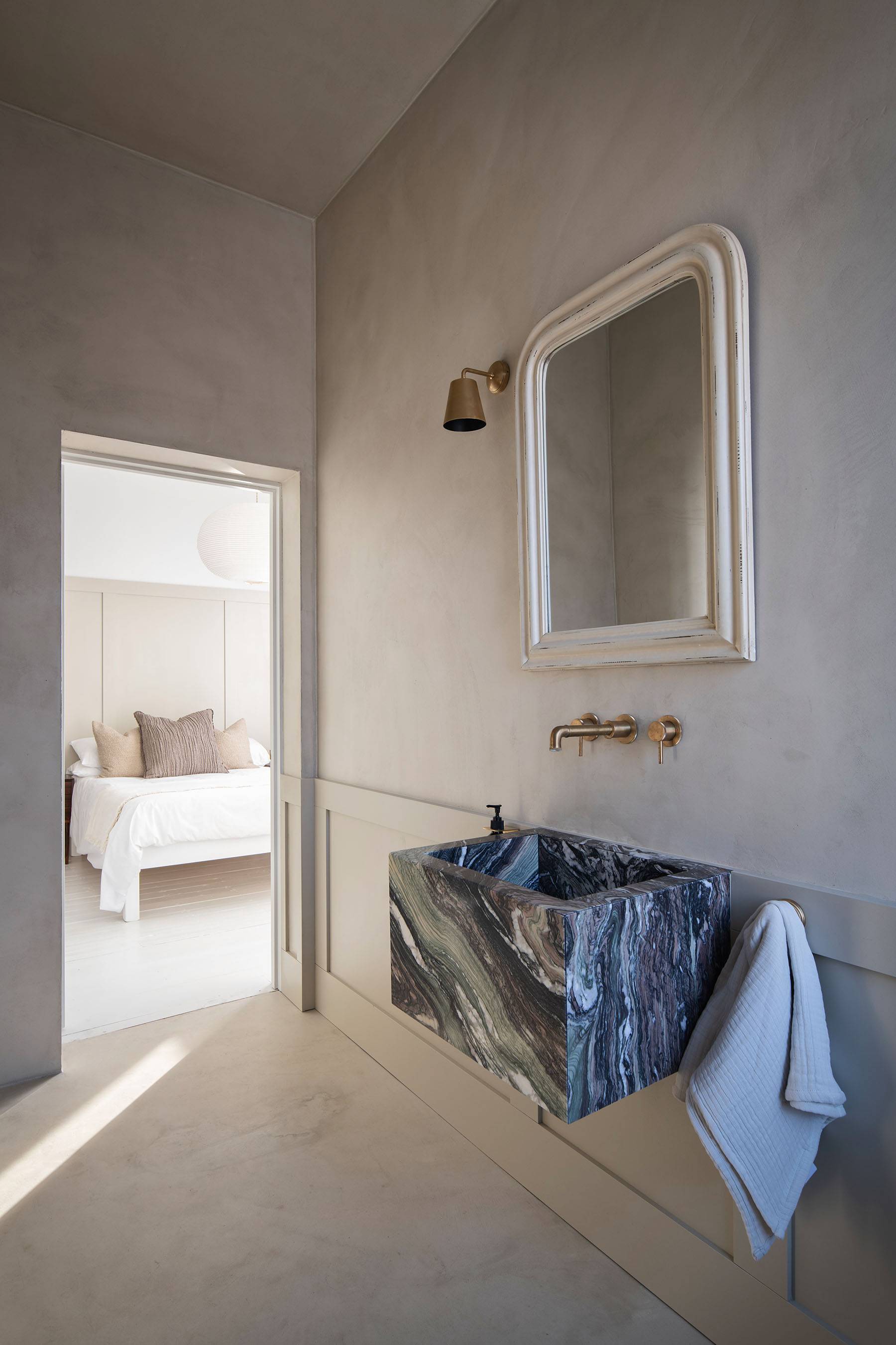 Dressing area nook featuring a vanity desk with a dark-veined marble countertop set against micro-cement walls, Love Locations SW16.