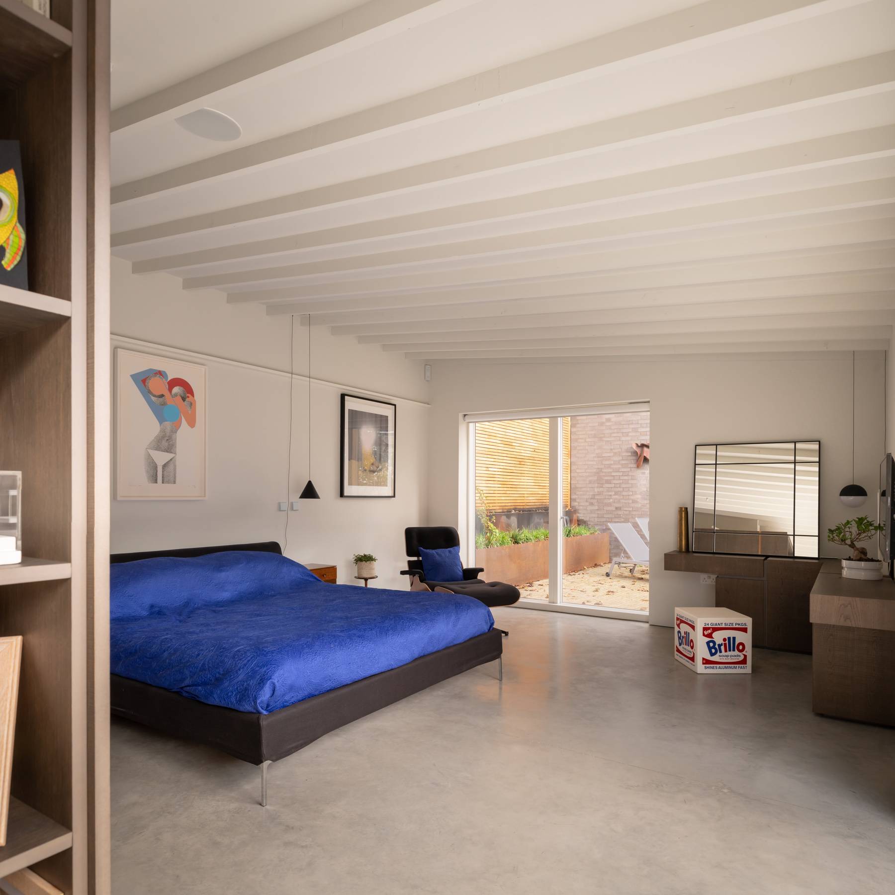 Spacious master bedroom with electric blue bed linen, exposed joist ceilings, and full-height wardrobes, Love Locations BN3.