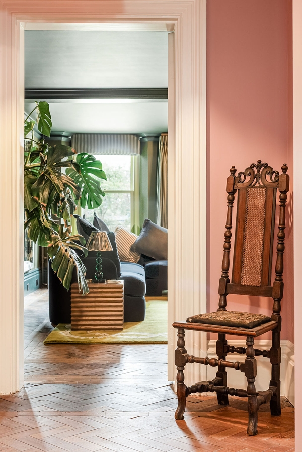 Light-filled transition space featuring a high-backed antique wooden chair and a large potted plant, available for filming through Love Locations.