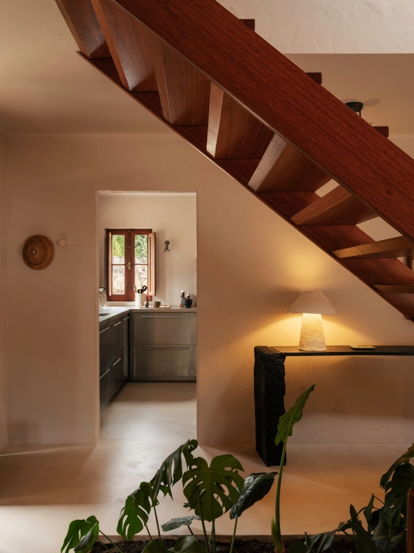 Architectural hallway transition looking under a timber staircase towards a sunlit doorway, Love Locations 2705-064.