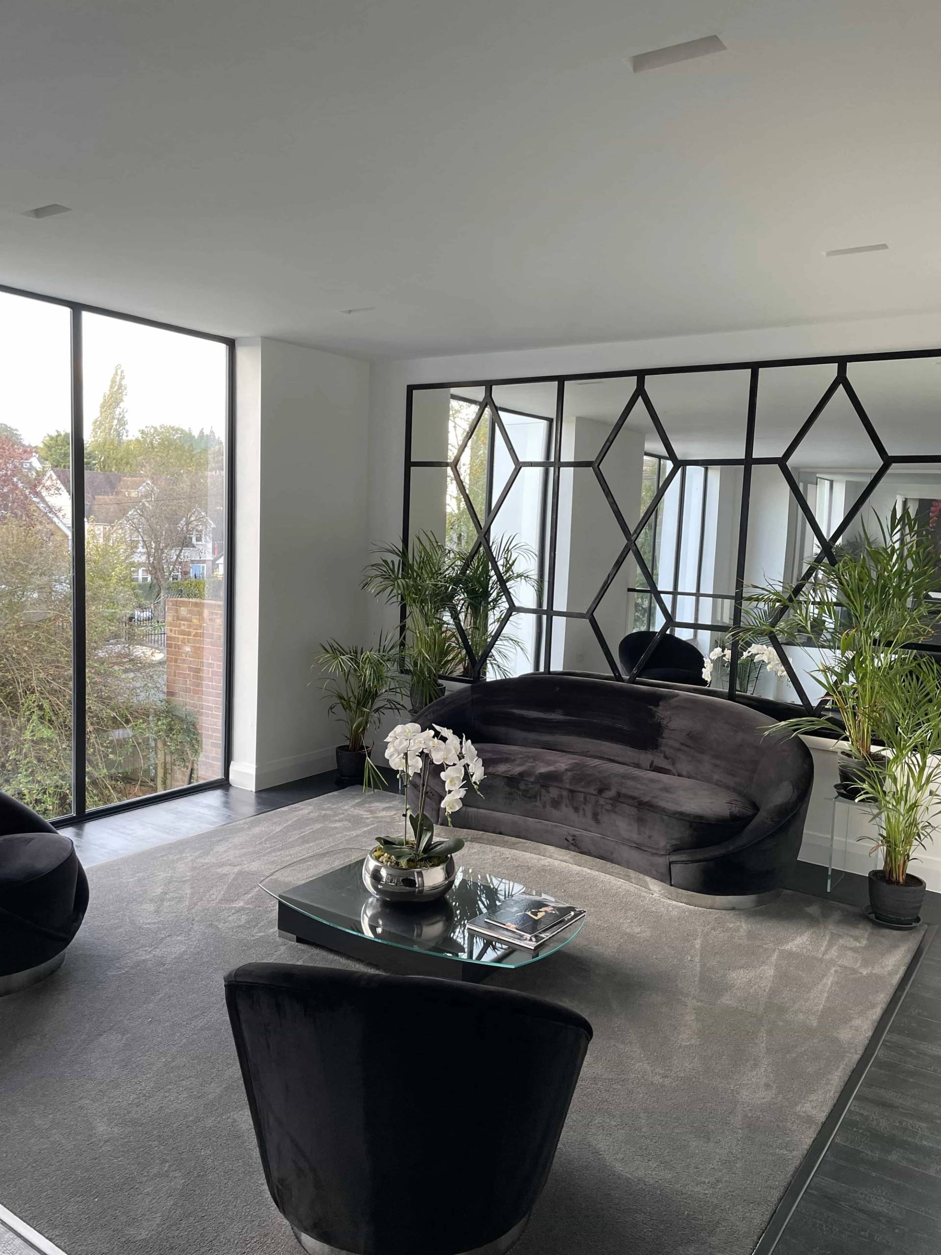 Living room featuring a dark curved velvet sofa set against geometric black mirrored wall panels, perfect for luxury brand campaigns, Love Locations IG10.