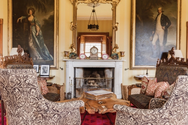 Ornate fireplace mantle framed by historic oil paintings and plush armchairs in a Scottish castle, Love Locations KY15.